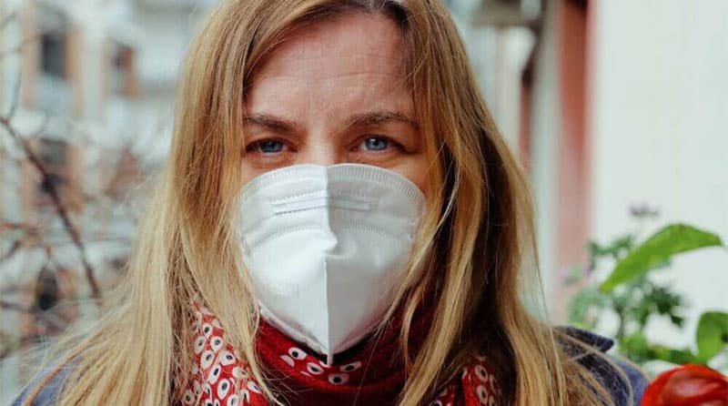 Blonde woman wearing white mask and red scarf
