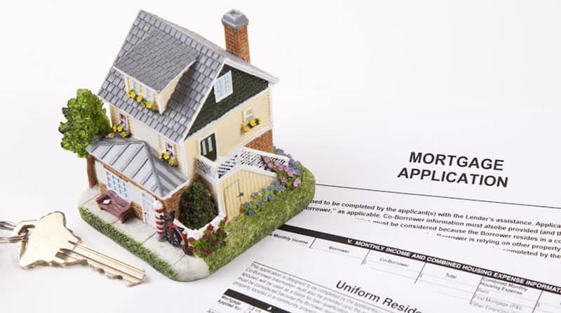 Photo of a mortgage application next to a key and a model house