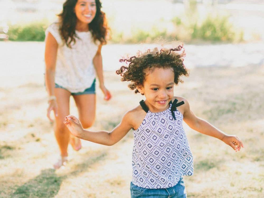 Young girl smilng as she runs from her mother