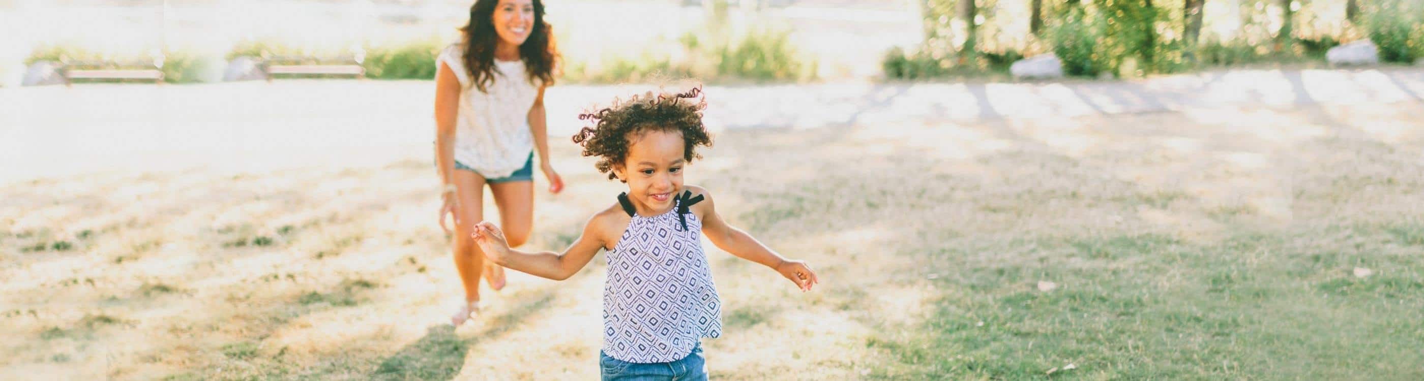 Young girl smilng as she runs from her mother