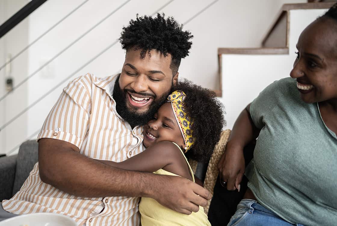 Dad and daughter hugging, mom looks on